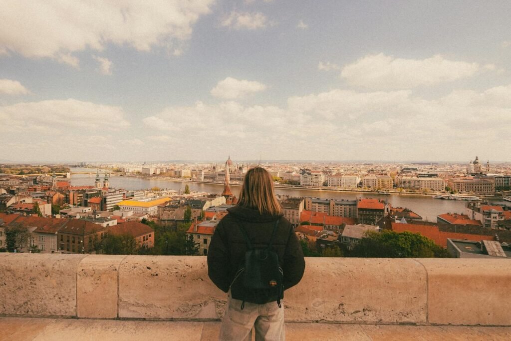 Woman admiring the panoramic view of Budapest from a high vantage point on a sunny day.