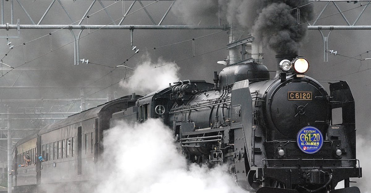 Steam locomotive releasing smoke and steam on a rail track, showcasing vintage train transportation.