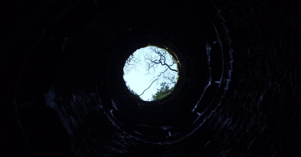 A dramatic upward view from inside a circular well in Sintra, Portugal.