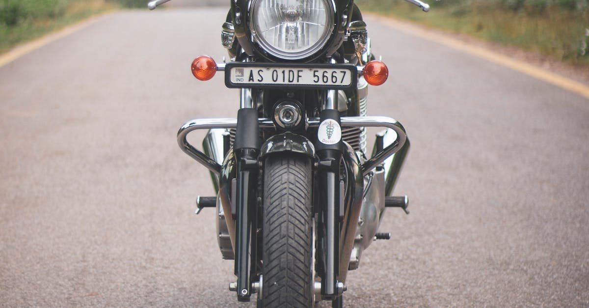 A classic vintage motorcycle parked on a quiet rural road surrounded by lush greenery.