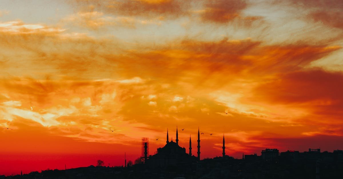 Dramatic silhouette of a mosque against a vibrant sunset sky in Istanbul, Turkey.