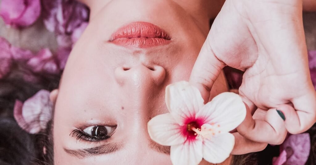 Elegant photoshoot featuring a woman holding a pink flower amidst petals.