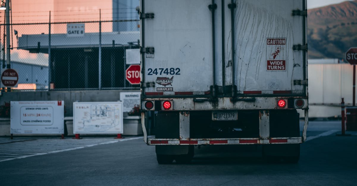 Semi truck parked at a loading dock with visible caution signs and industrial surroundings.