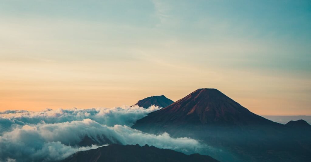 Beautiful sunrise view of Mount Sindoro with clouds and serene landscape in Java, Indonesia.