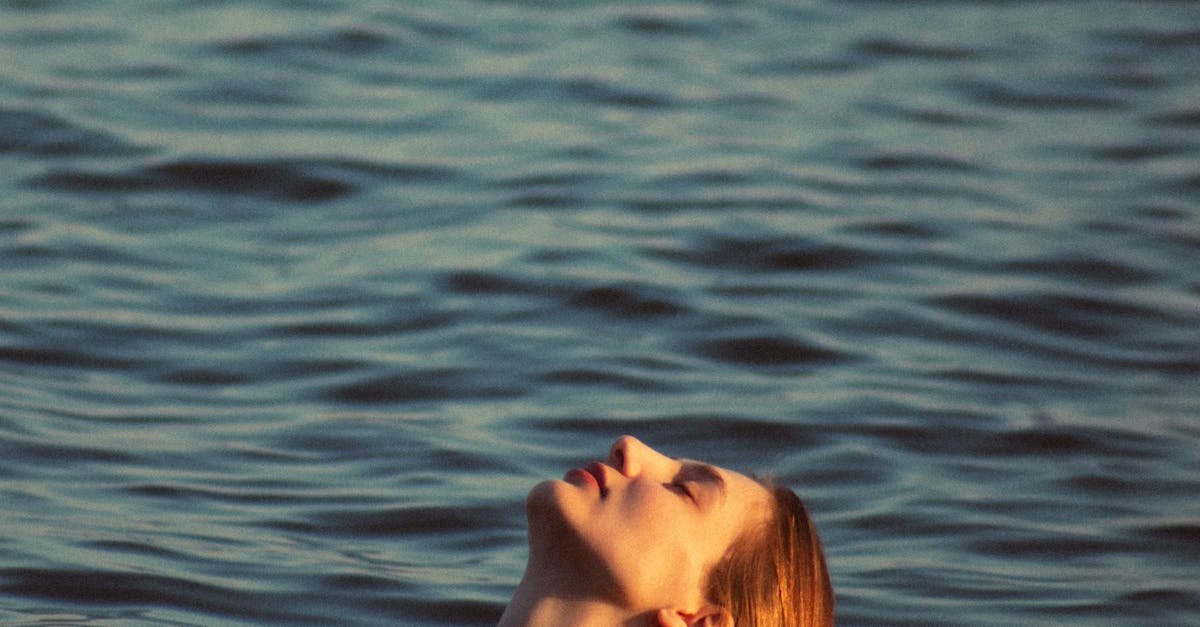 A woman peacefully emerging from calm ocean waters at sunset, creating a serene atmosphere.