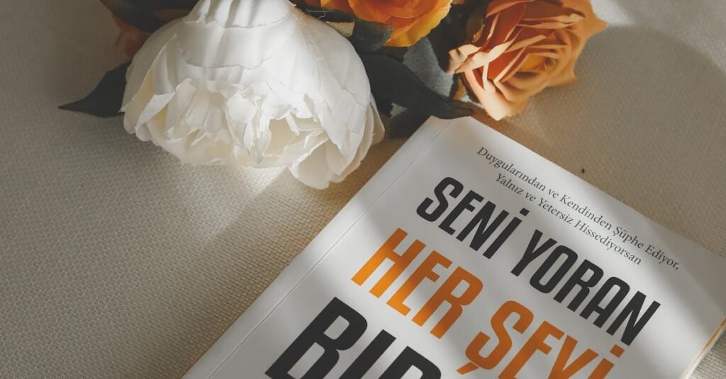 Artistic arrangement of roses and a Turkish book on a white surface.