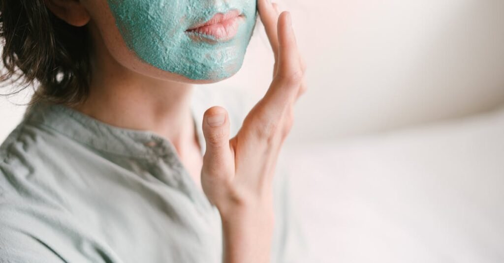 Young woman applies a rejuvenating facial mask indoors for skin care and relaxation.