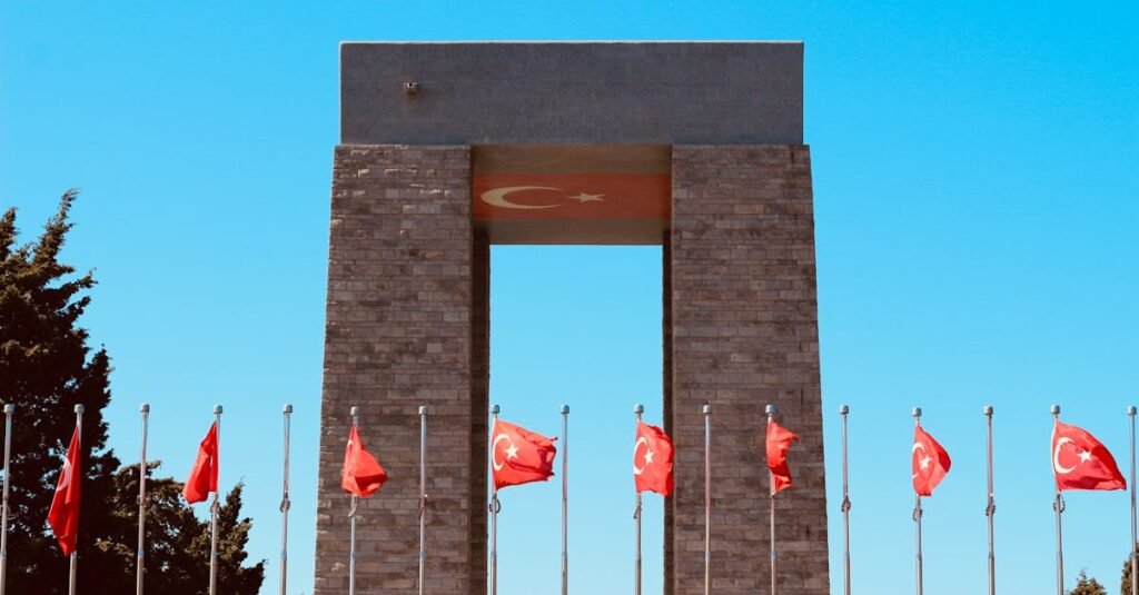The Turkish national monument with multiple flags waving under a clear blue sky, symbolizing patriotism.