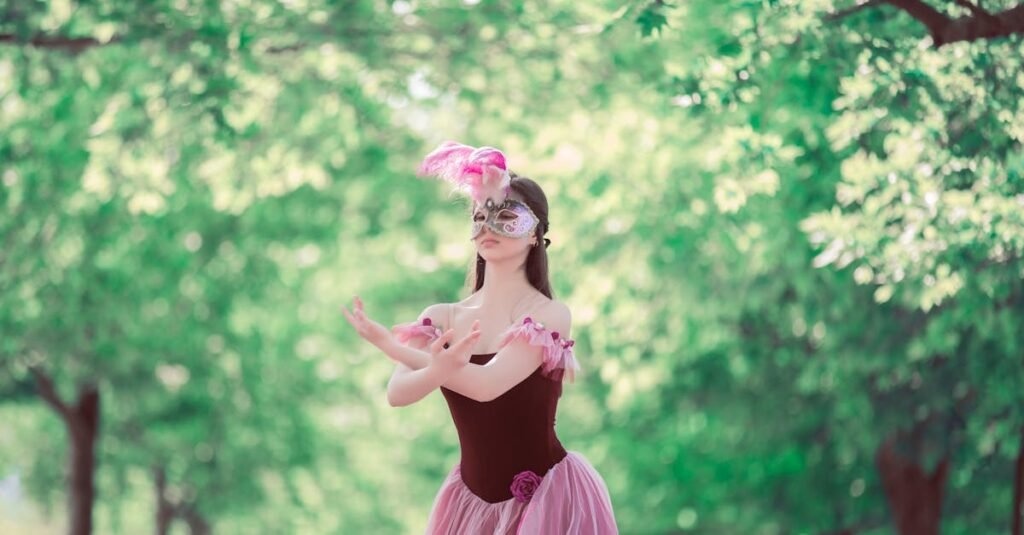 A woman in an elegant masquerade costume poses amidst lush green trees on a sunny day.