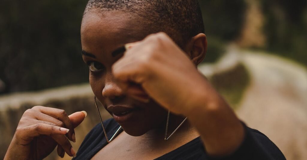A strong, confident woman posing outdoors with a blurred natural background.