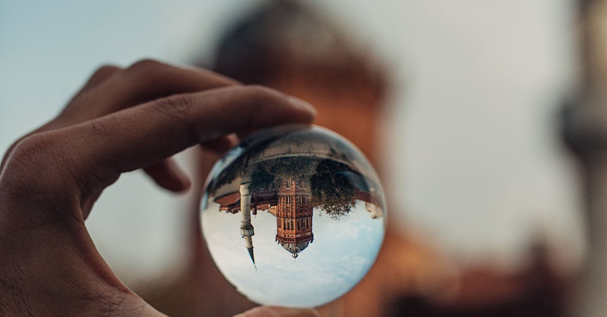 A hand holds a lensball capturing an inverted historic building in Istanbul, creating a dreamy effect.