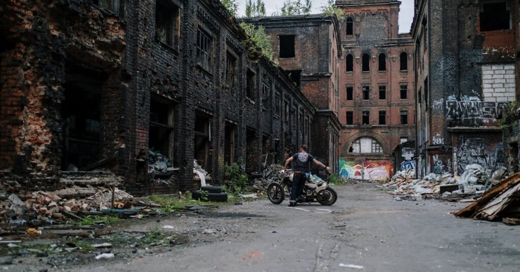 Motorcyclist exploring an abandoned building with graffiti and decay.