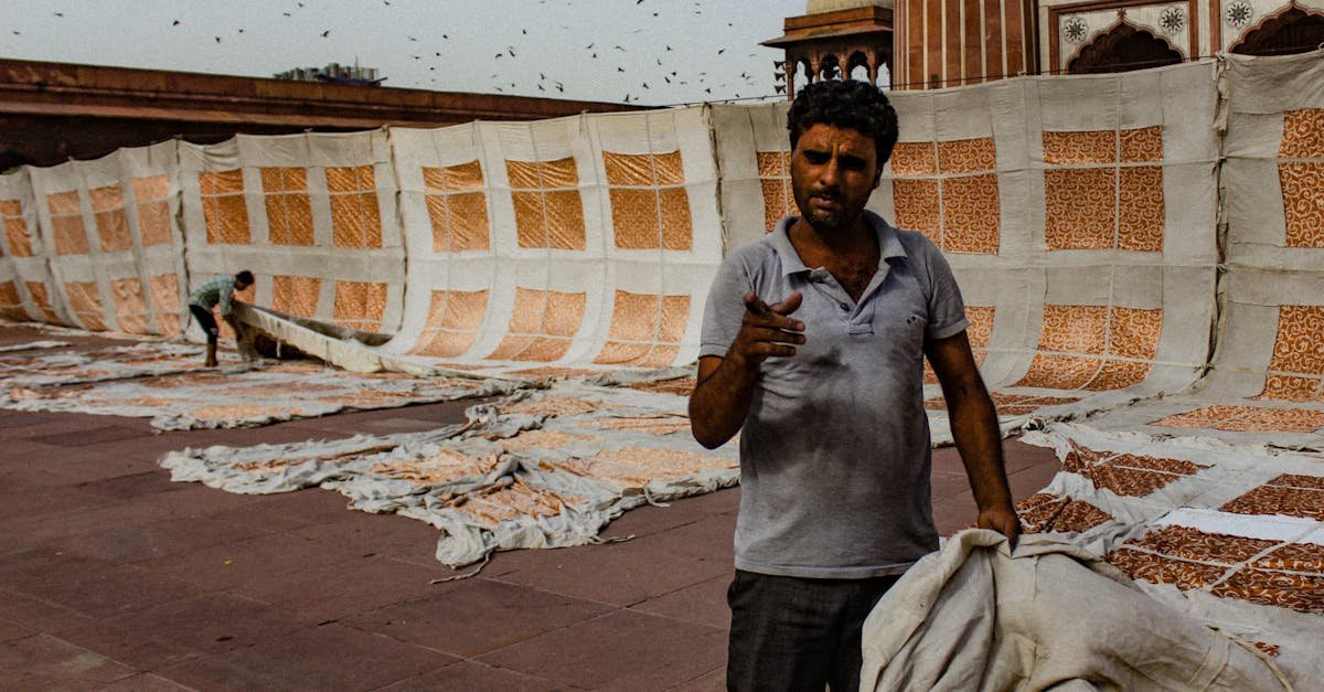 A man arranging and drying textiles at a historical site, showcasing traditional techniques.