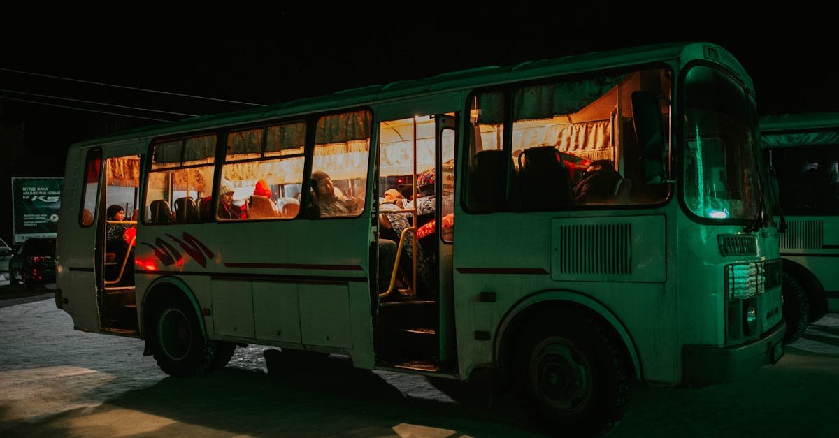 A bus parked at night with passengers visible inside, creating a warm, inviting glow.