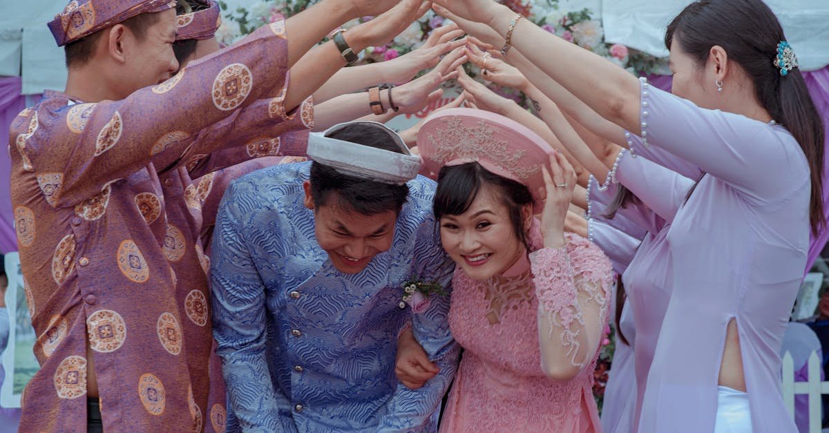 Happy Vietnamese couple celebrates their wedding with friends in traditional attire outdoors.