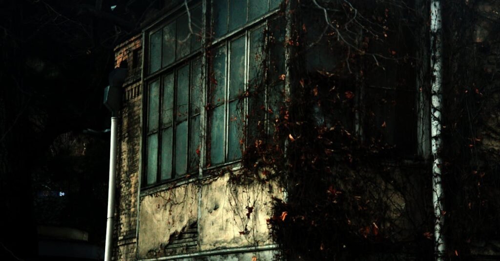 A dark, abandoned building covered with vines in an urban setting, creating an eerie atmosphere.