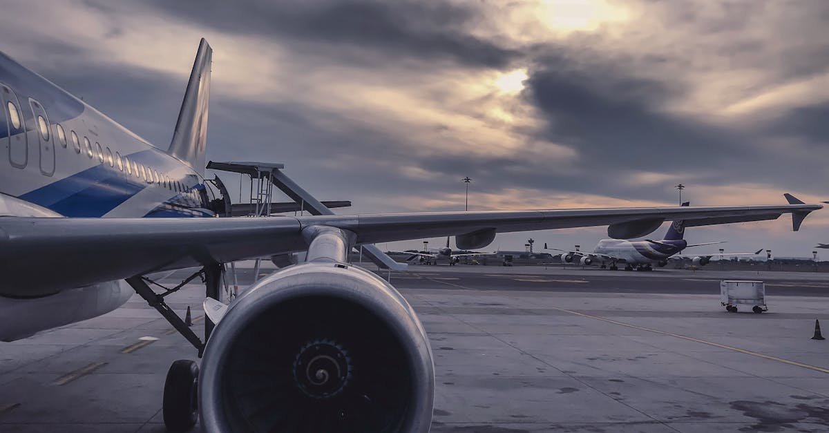 A passenger airplane is parked on the tarmac at sunset, with another aircraft in the background.