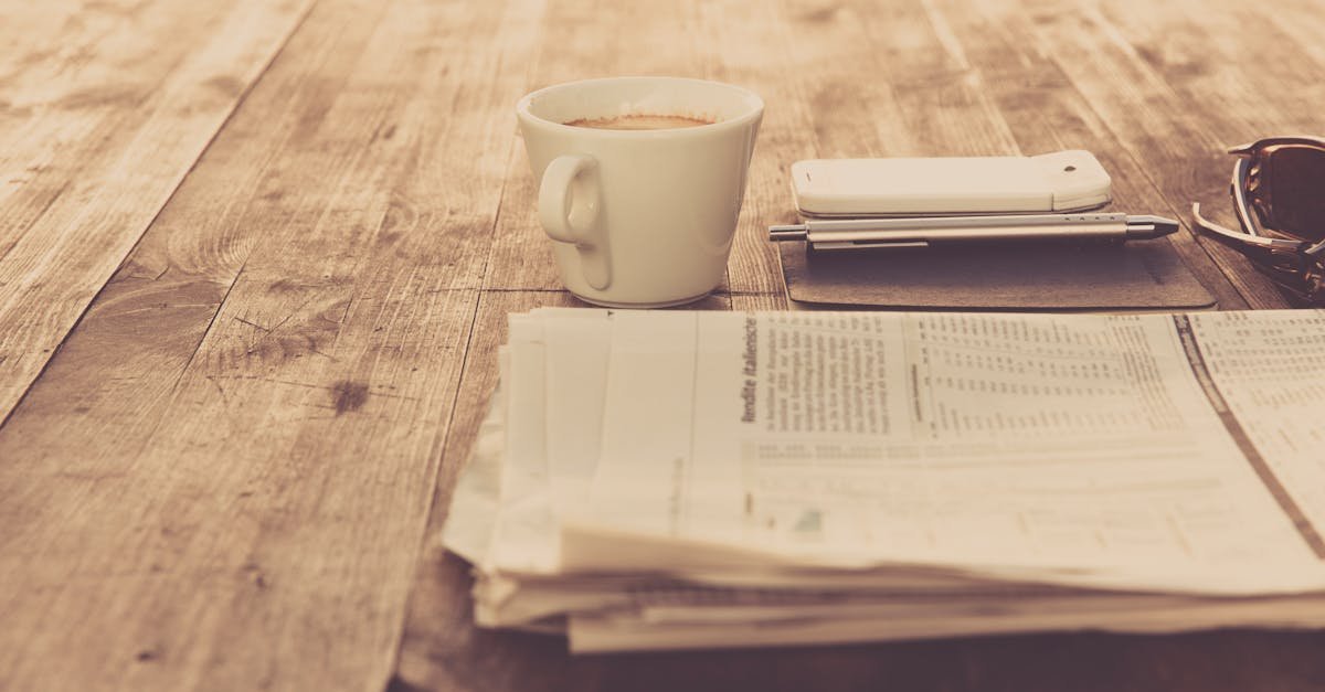 A warm vintage morning setup with coffee, newspaper, and smartphone on wooden table.