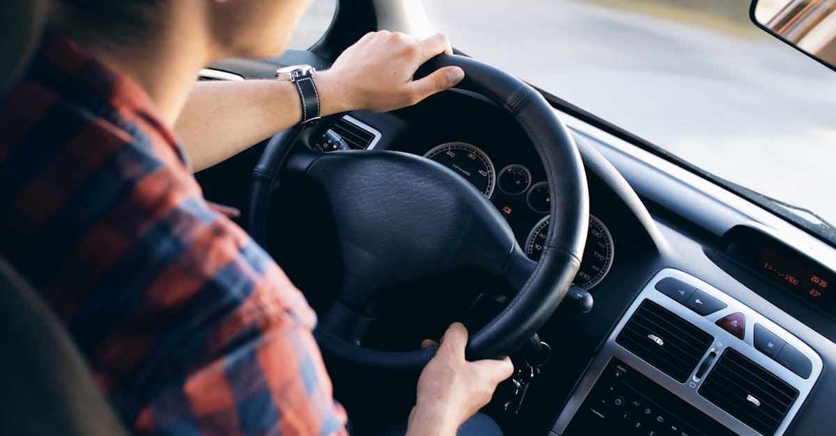 Close-up view of a man driving a modern car, showing dashboard and steering details.