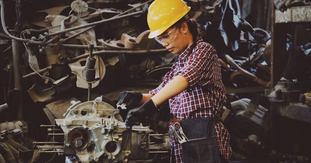 Woman engineer wearing safety gear, working on machine repair in an industrial setting.