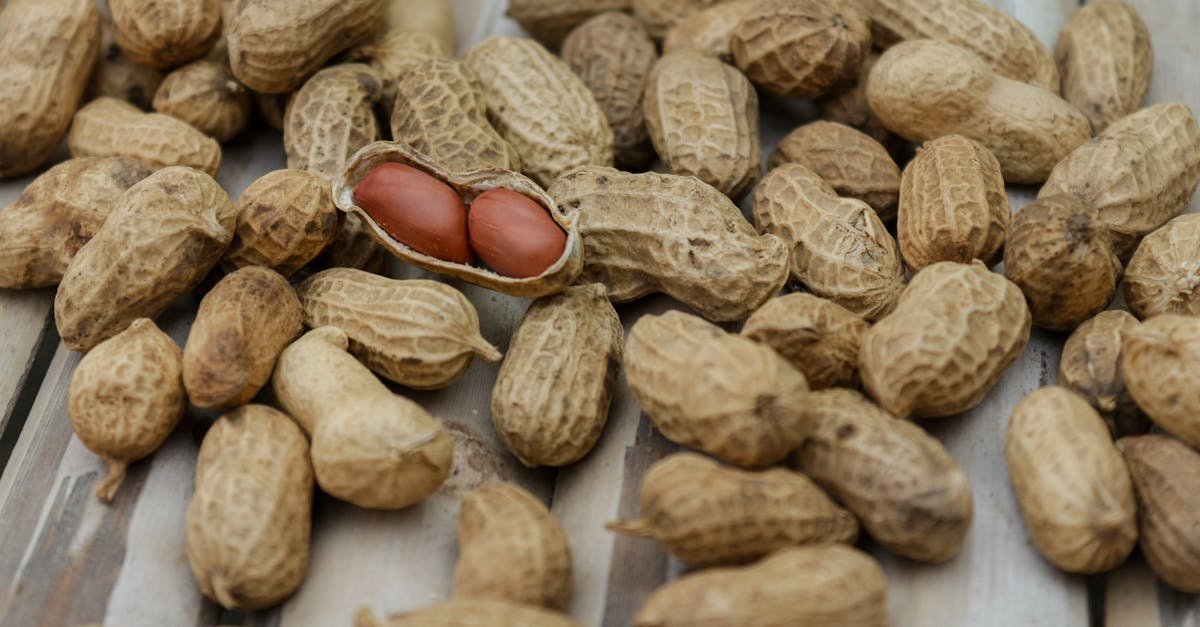 A detailed close-up of peanuts in their shells scattered on a wooden surface.