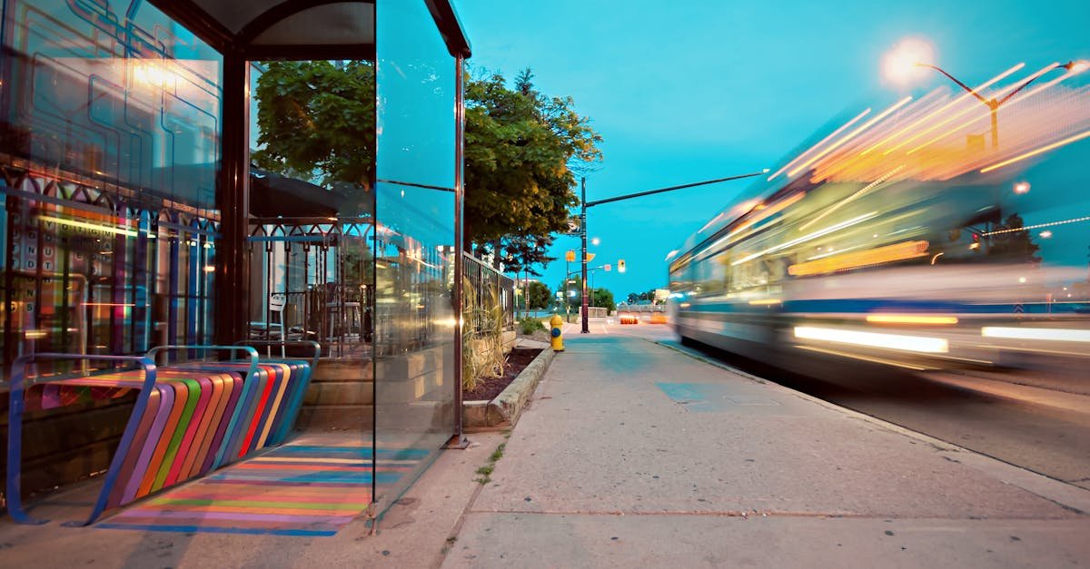 Colorful city bus stop with vibrant benches, blurred motion of a passing bus at dusk.