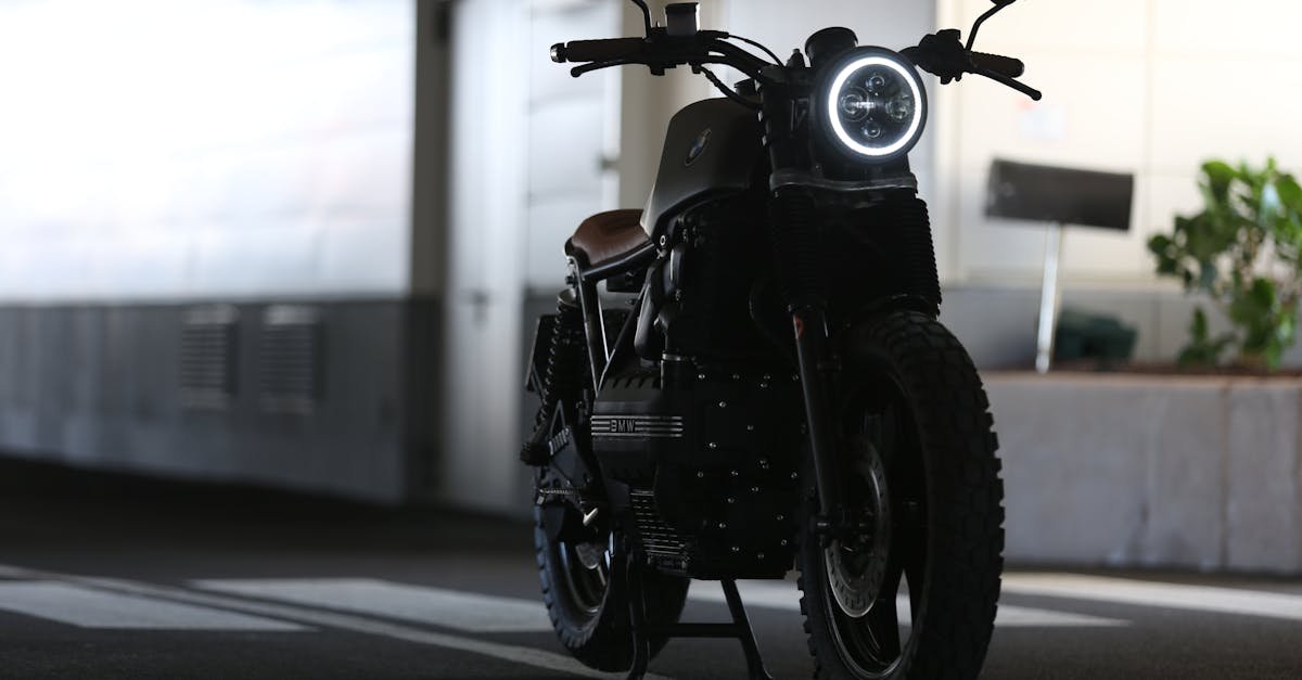 A sleek cafe racer motorcycle parked indoors with strong lighting contrast.