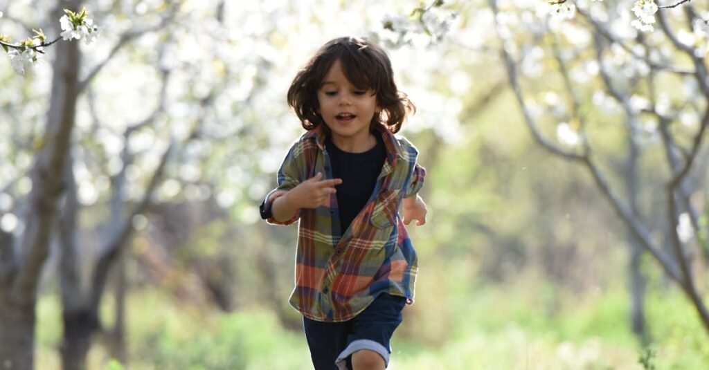 Happy child running in a sunlit orchard during springtime, surrounded by blooming trees.