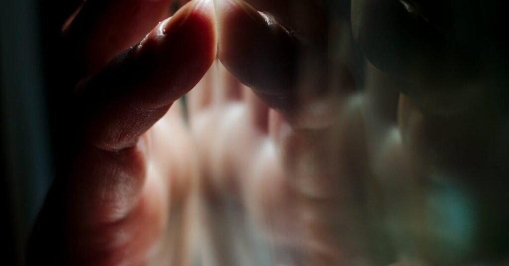 A hand pressing against a glass surface with vivid reflections, creating a moody atmosphere.