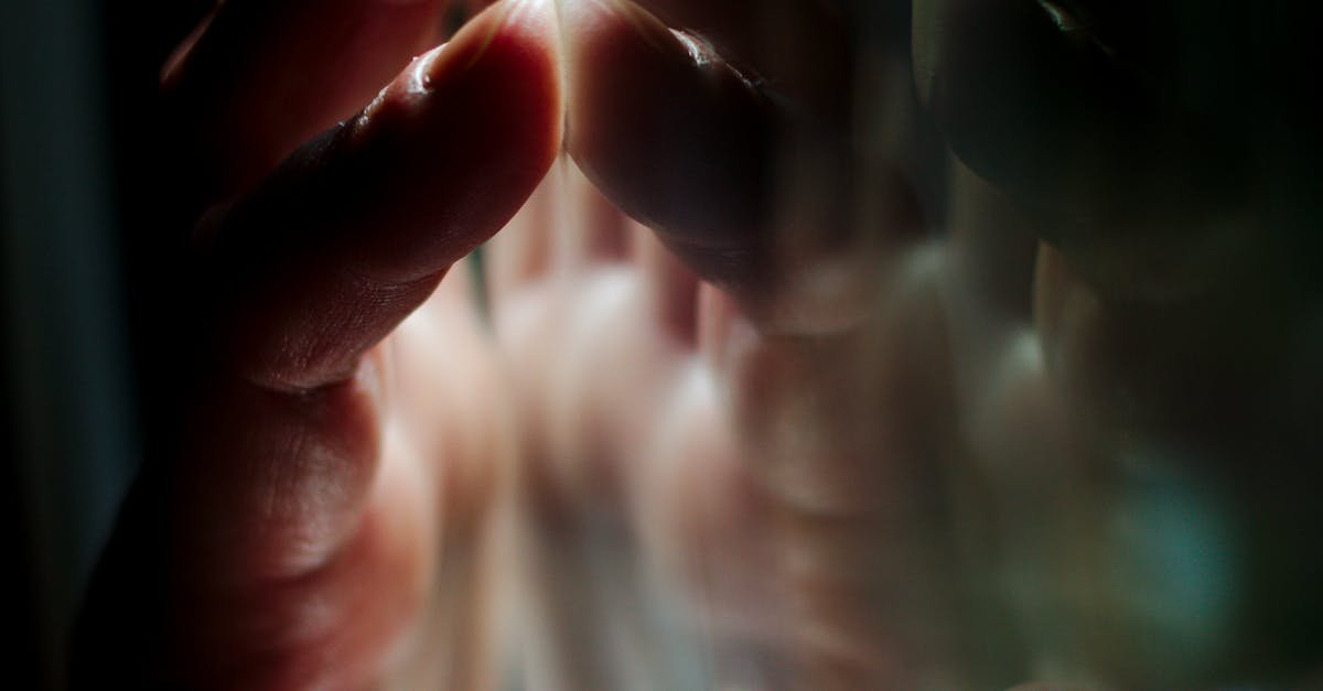 A hand pressing against a glass surface with vivid reflections, creating a moody atmosphere.