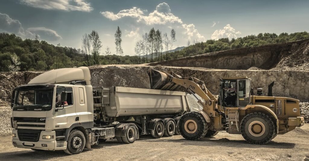 Excavator and truck working together in a quarry, showcasing industrial equipment and operations.