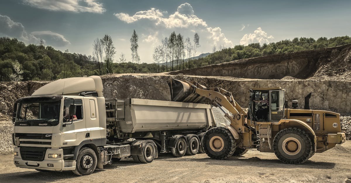 Excavator and truck working together in a quarry, showcasing industrial equipment and operations.