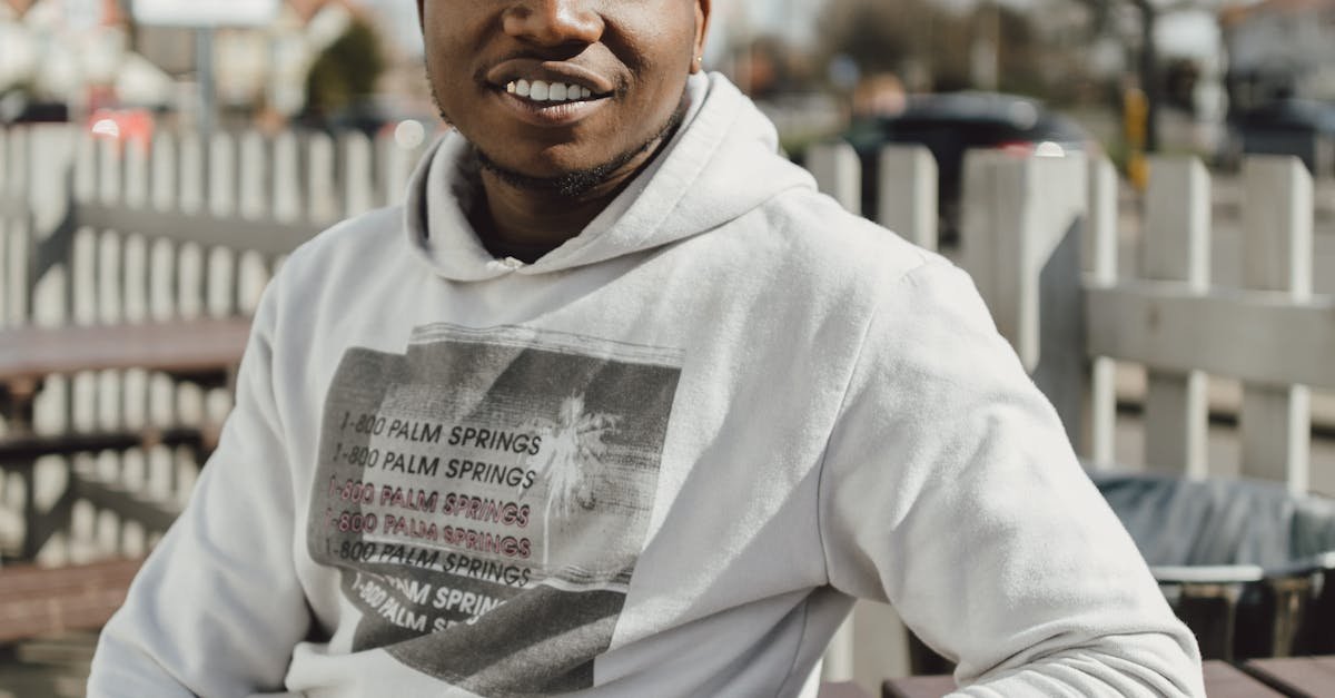 Smiling adult man in a hoodie outdoors, enjoying a sunny day.