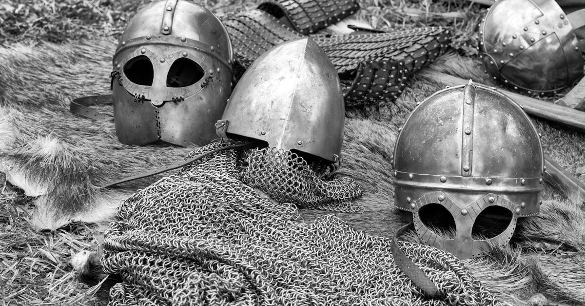 Close-up of historical medieval helmets and armor in black and white.
