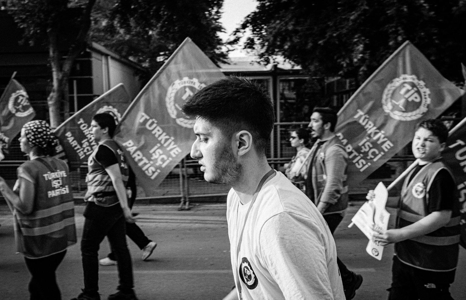 A black and white photo capturing a political demonstration in Adana, Türkiye with flag-waving participants.