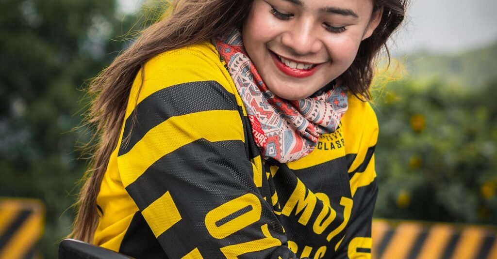 Young woman in bright attire smiling on motorcycle, enjoying the day.