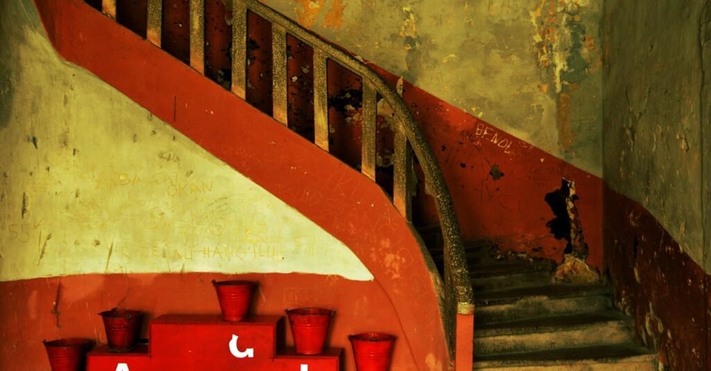 An old, rustic staircase with red decor buckets inside a vintage building, exuding a nostalgic feel.