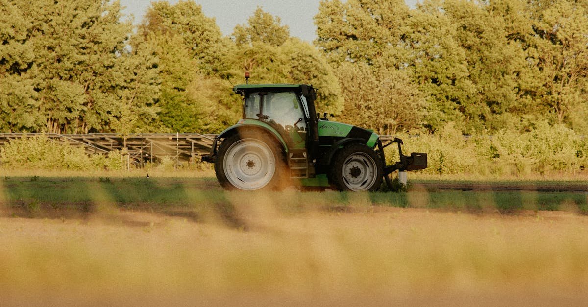 Green tractor working on a farm field in sunny weather. Ideal for agriculture and rural themes.