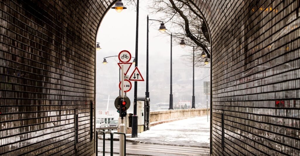 Atmospheric view through a brick tunnel to snowy street with road signs.