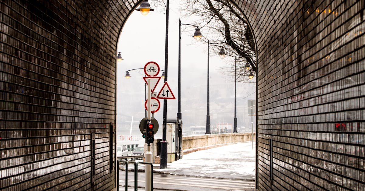 Atmospheric view through a brick tunnel to snowy street with road signs.