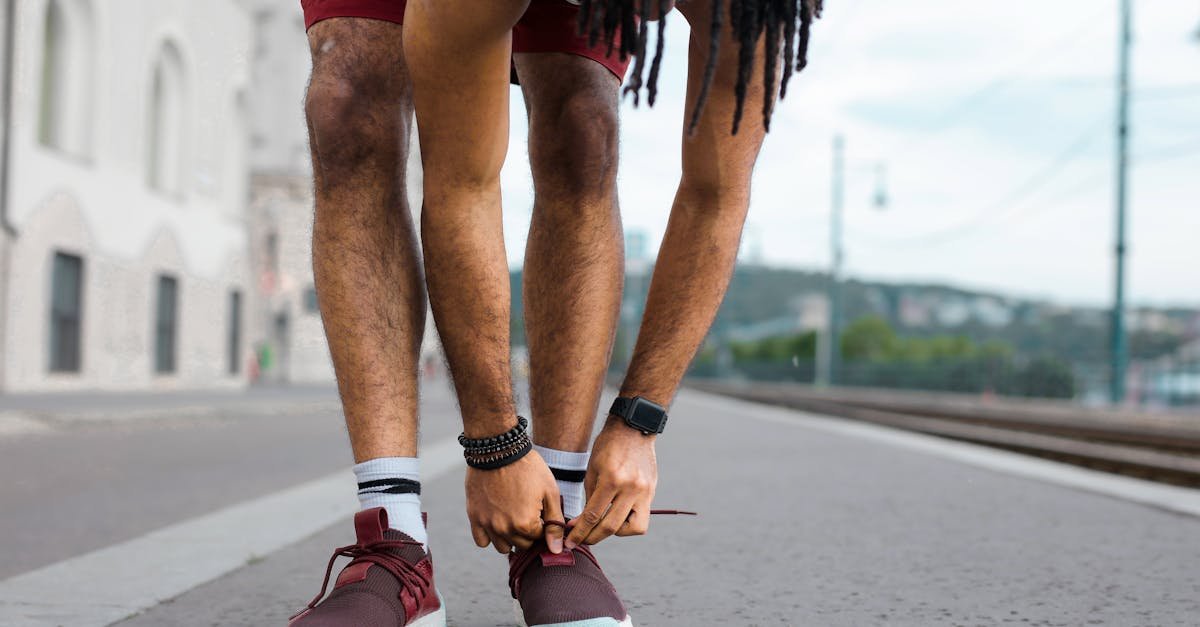Close-up of a young man tying his sneakers on a street, preparing for an outdoor run.