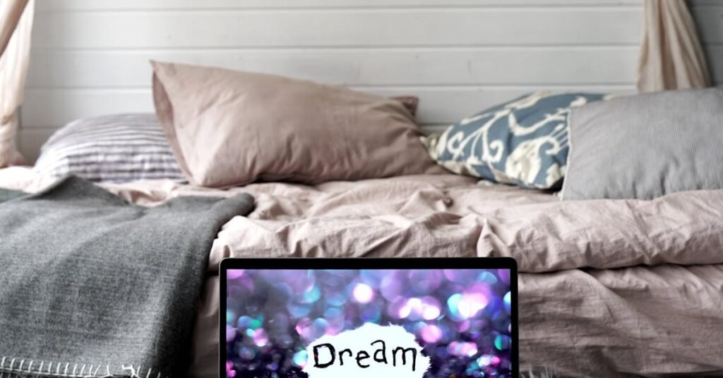 A serene bedroom with a laptop displaying 'Dream' amidst cozy pillows and soft textiles.