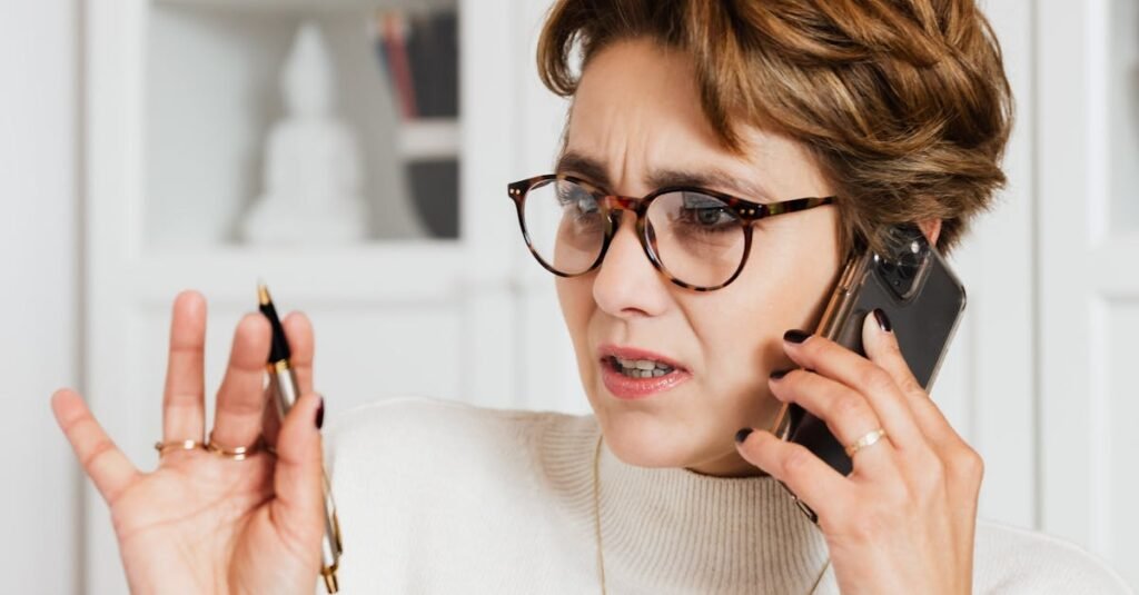Businesswoman expressing concern while on a phone call indoors, holding a pen with an engaged expression.