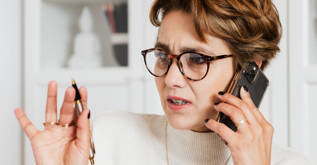 Businesswoman expressing concern while on a phone call indoors, holding a pen with an engaged expression.