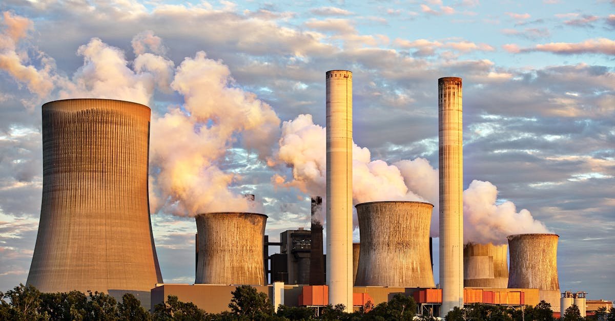 View of a power plant with smoke emissions under a cloudy sky, depicting industrial energy production.