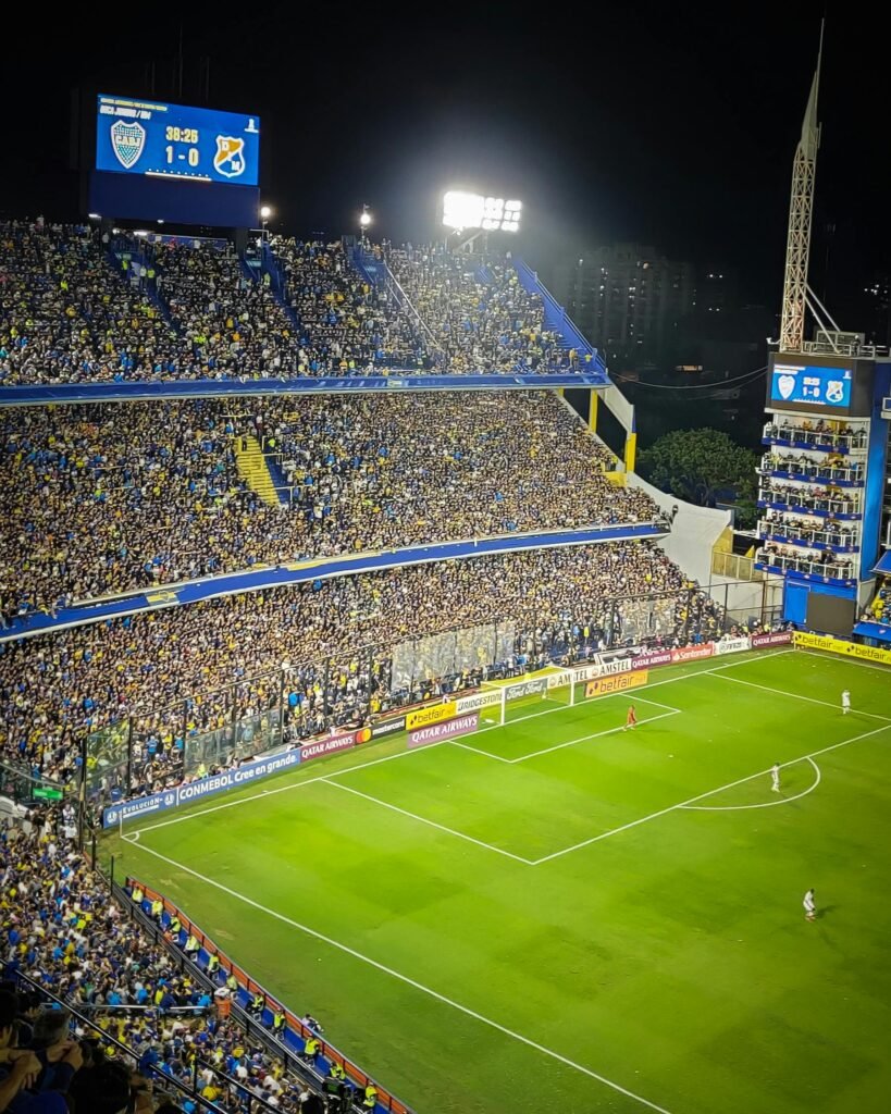 Vibrant soccer game at La Bombonera Stadium in Buenos Aires. Enthusiastic fans fill the stands under bright lights.