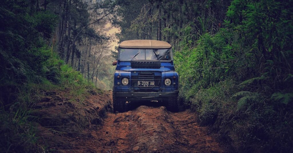 Off-road vehicle traversing a rugged dirt path through lush forest in Parongpong, Indonesia.