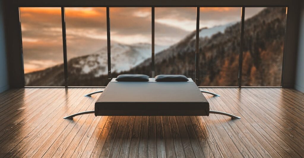 Minimalist bedroom with large windows offering a breathtaking mountain view during sunset.