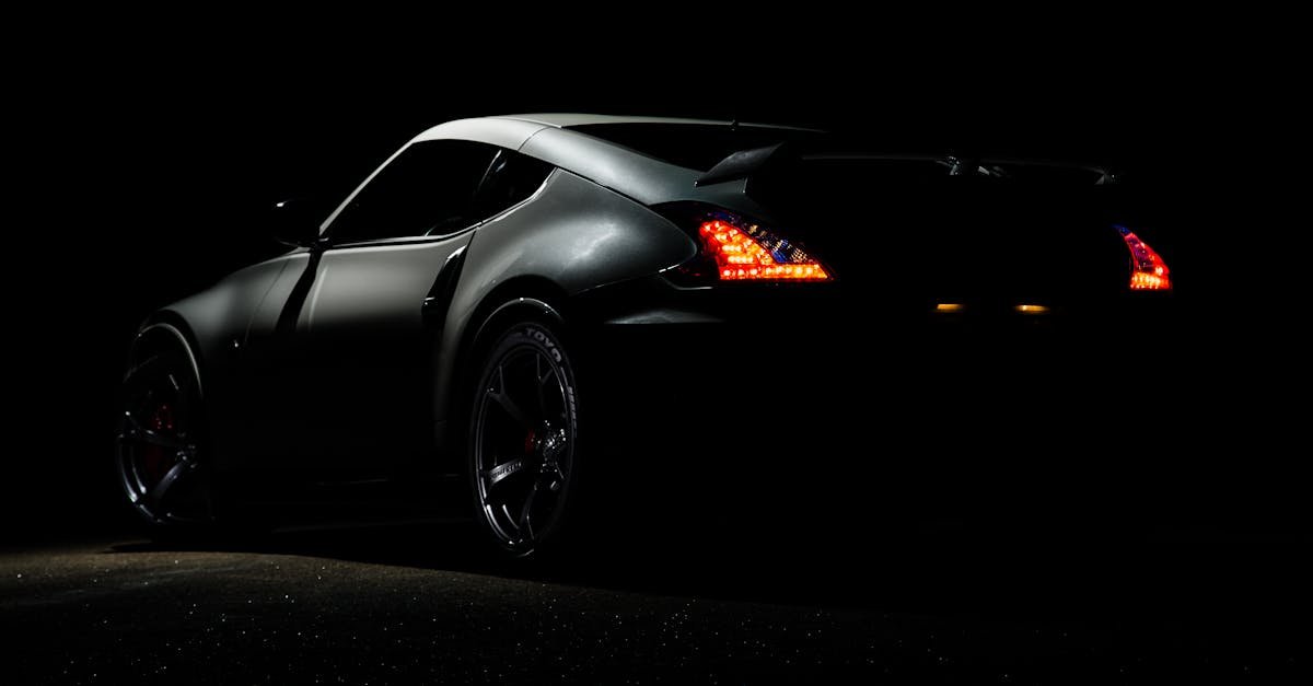 A dramatic shot of a Nissan 370Z sports car illuminated in darkness with vibrant tail lights.