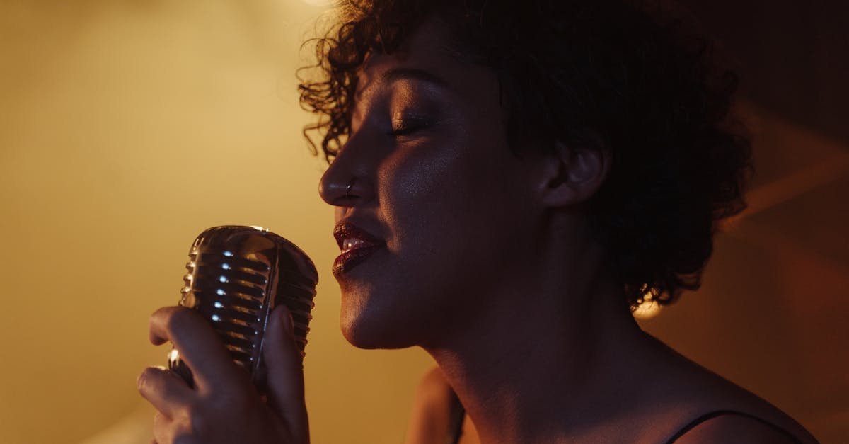 Close-up of a woman passionately singing into a vintage microphone under warm lighting.